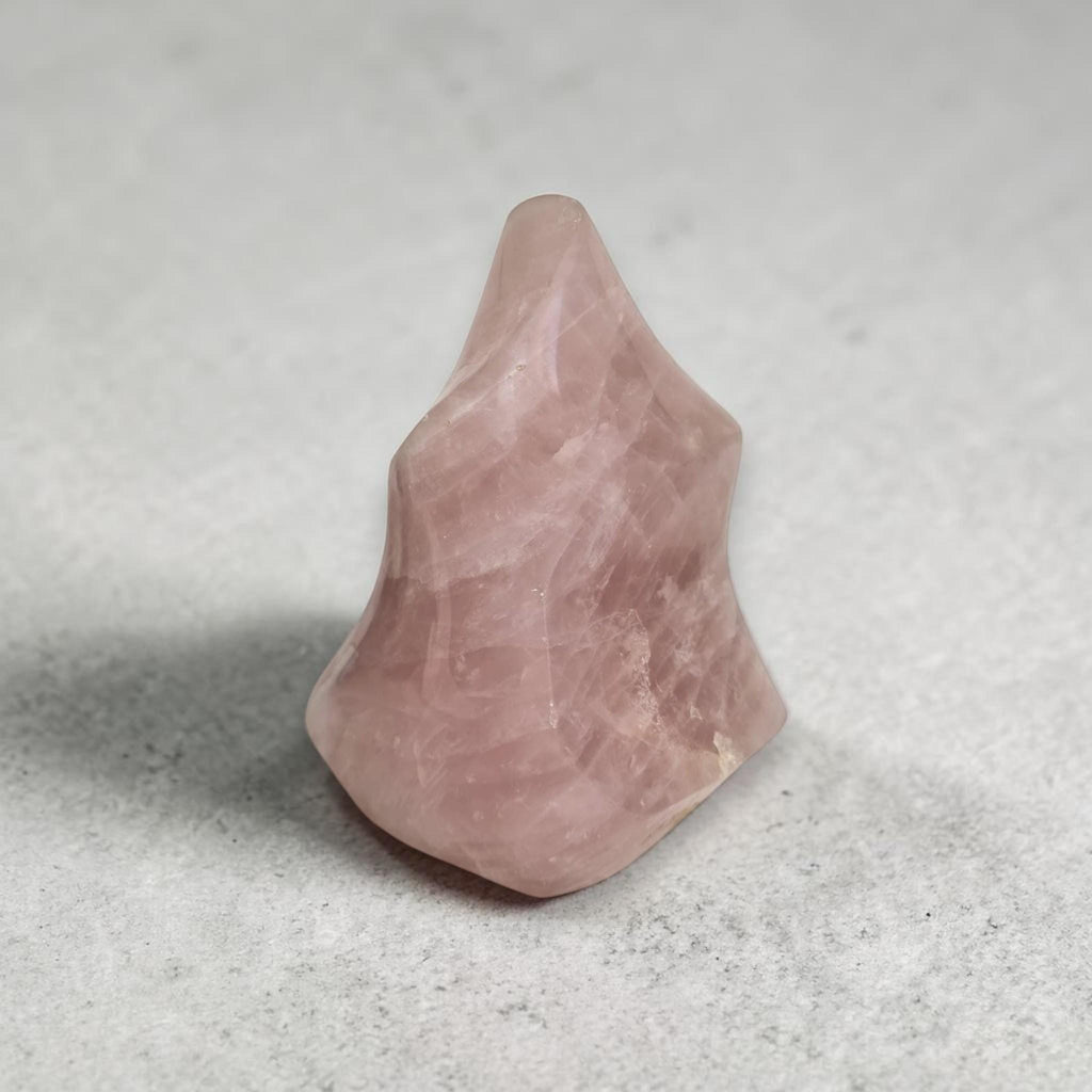 Rose quartz flame-shaped crystal, pink translucent with visible internal lines and shine