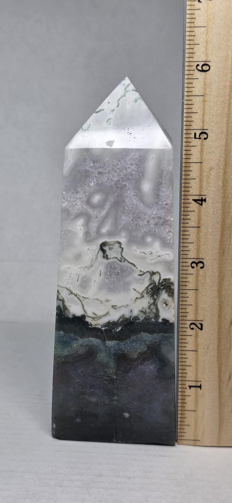 Moss agate tower with ruler for scale, white-gray marbling, dark base and green inclusions