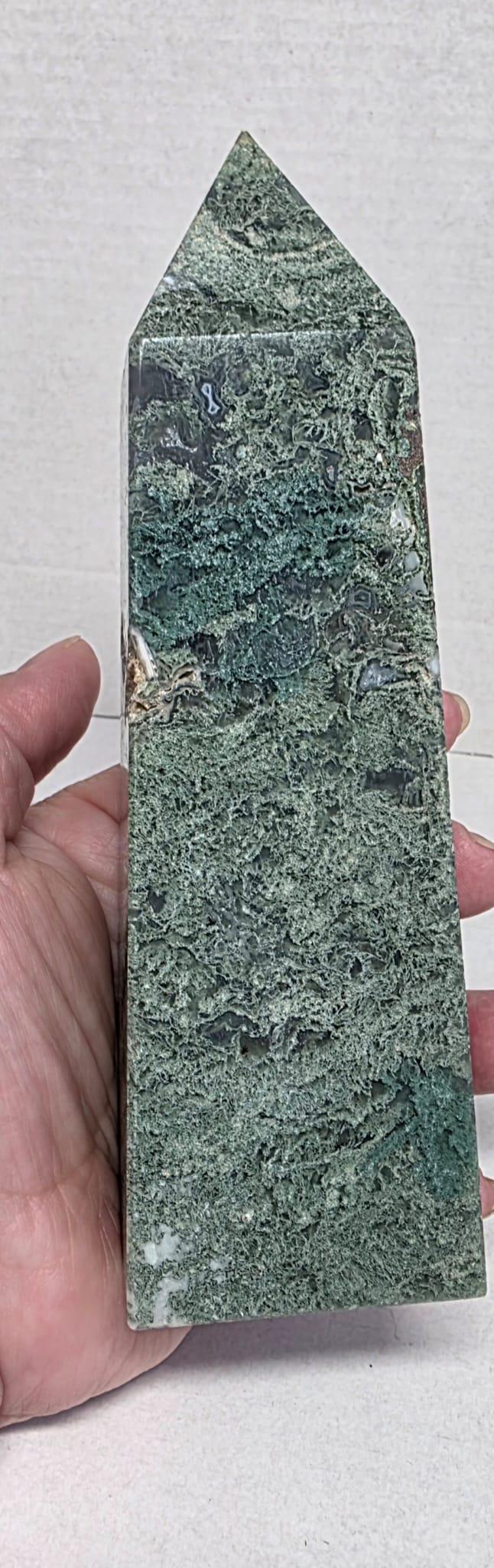 Green moss agate crystal point obelisk with speckled texture, held in hand