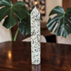 Polished jasper crystal obelisk with pointed tip, light base and black speckles.