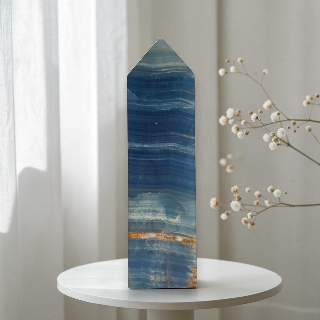 Blue stone crystal obelisk with pointed top and banded wave patterns