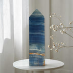 Blue stone crystal obelisk with pointed top and banded wave patterns