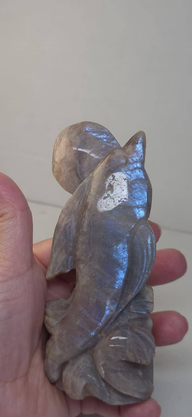 Dolphin crystal sculpture in brown stone with blue highlights, held in hand