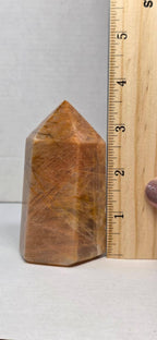 Obelisk point tower stone beside ruler, polished brown-gold with pointed top