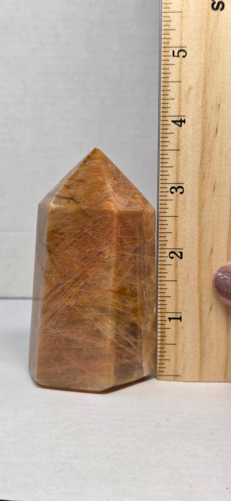 Obelisk point tower stone beside ruler, polished brown-gold with pointed top