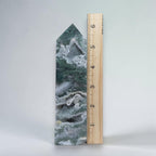Green moss agate drusy obelisk tower crystal beside a wooden measuring ruler