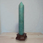 Green amazonite crystal obelisk with pointed top on dark wooden base