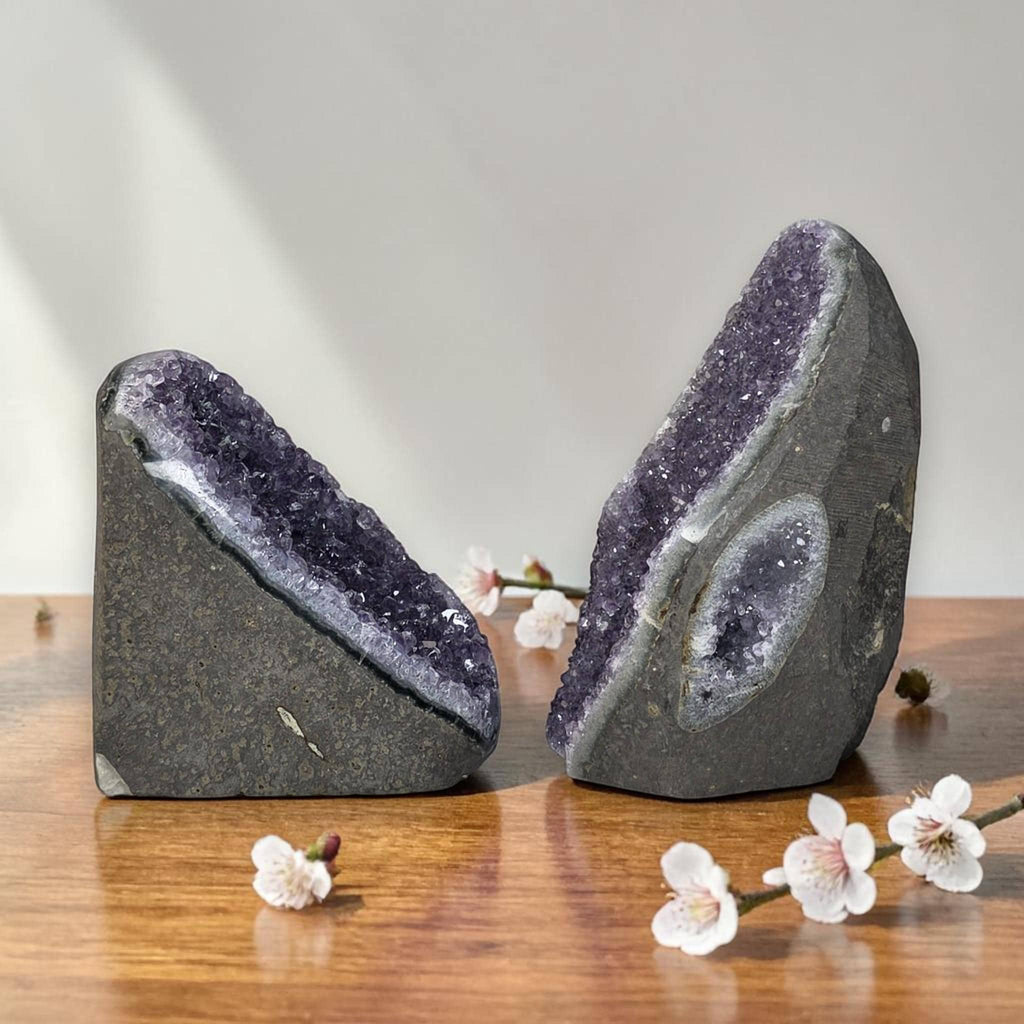 Two amethyst druzy freeform crystals on a tabletop, purple sparkling faces on dark bases