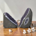 Two amethyst druzy freeform crystals on a tabletop, purple sparkling faces on dark bases