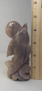 Dolphin crystal carving in brown stone, placed beside a measuring ruler