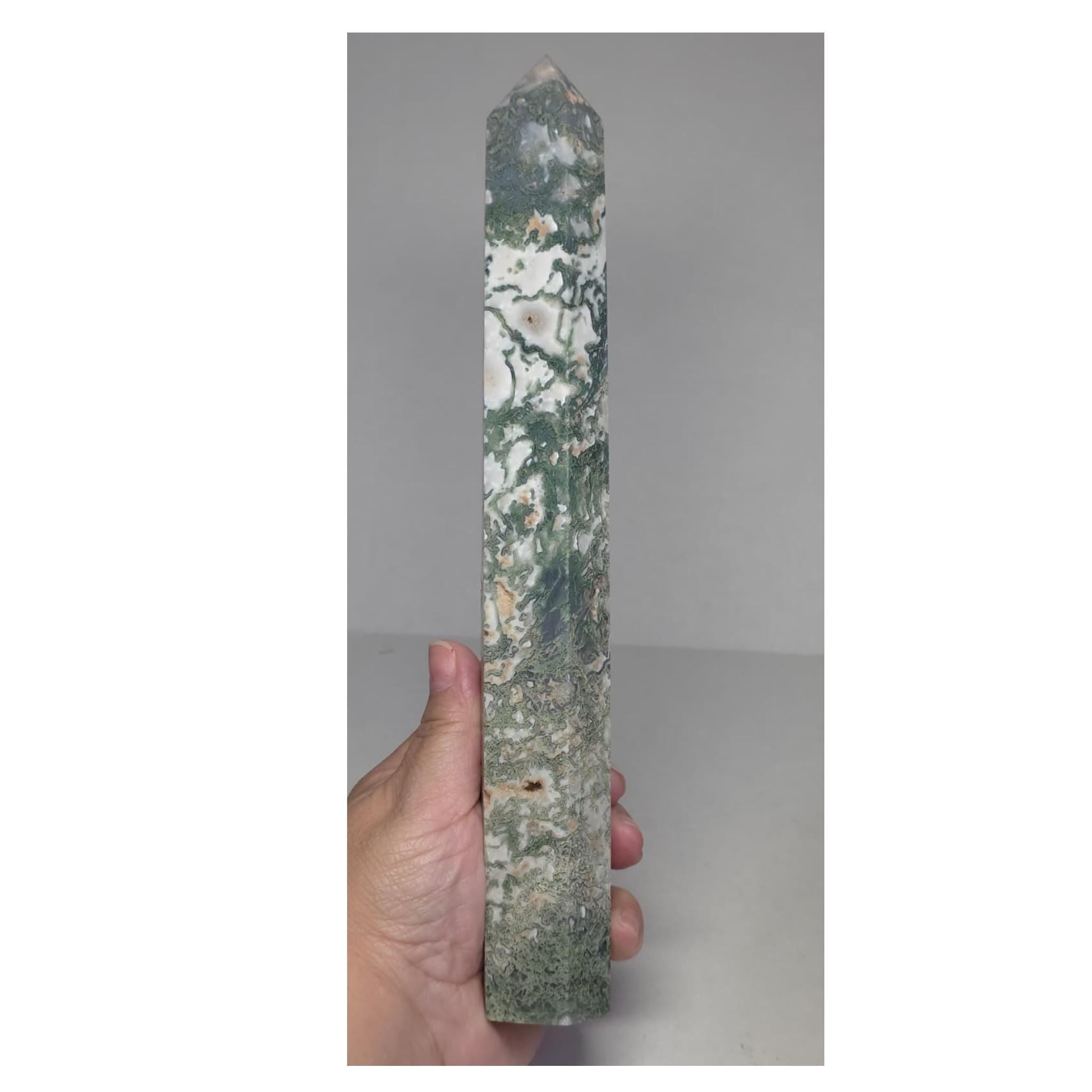 Moss agate obelisk point held in hand, green veining on light stone.