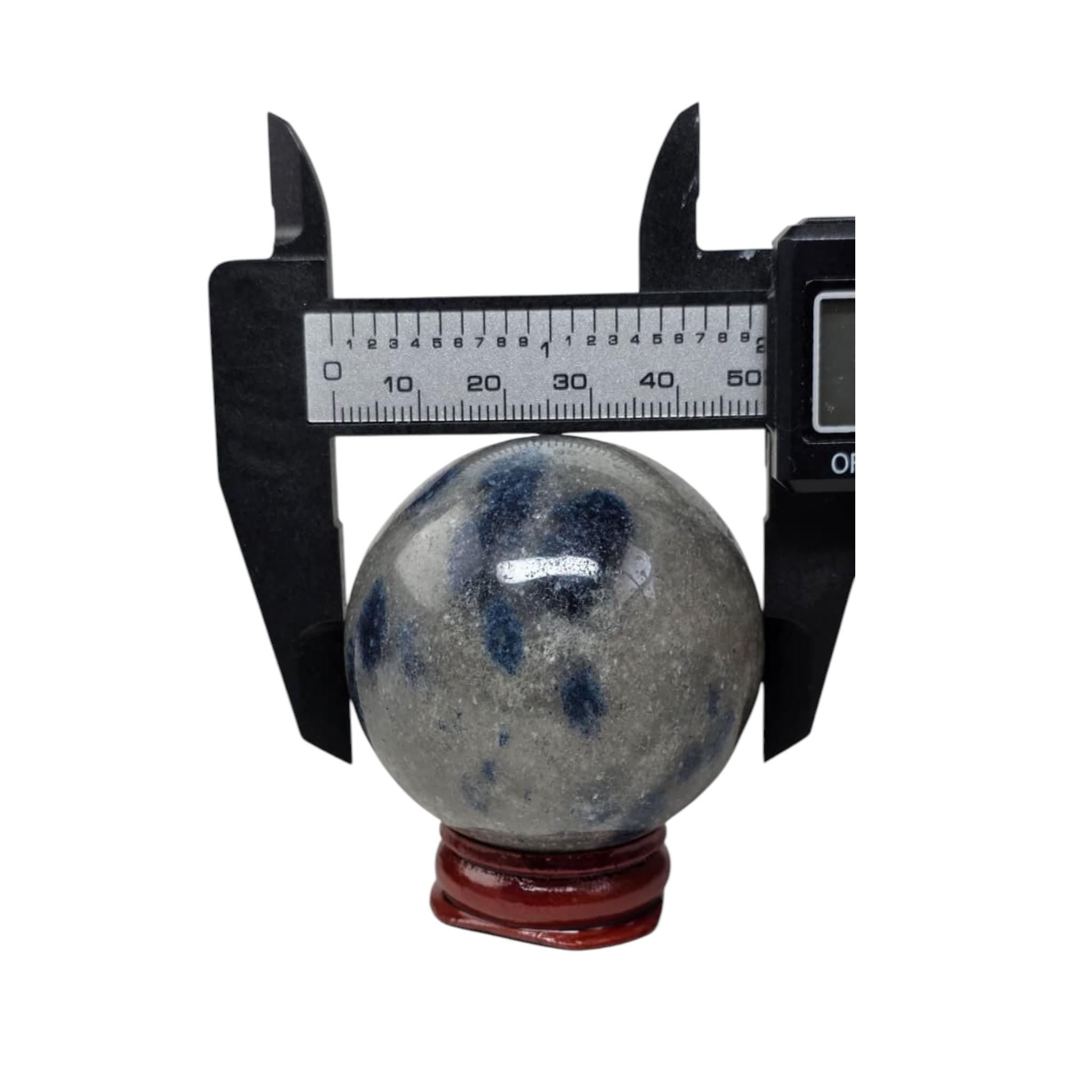 Granite crystal sphere with blue mottling, caliper measurement, on red stand