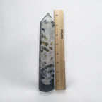 Natural crystal obelisk tower with white and gray bands and dark green specks, pointed tip