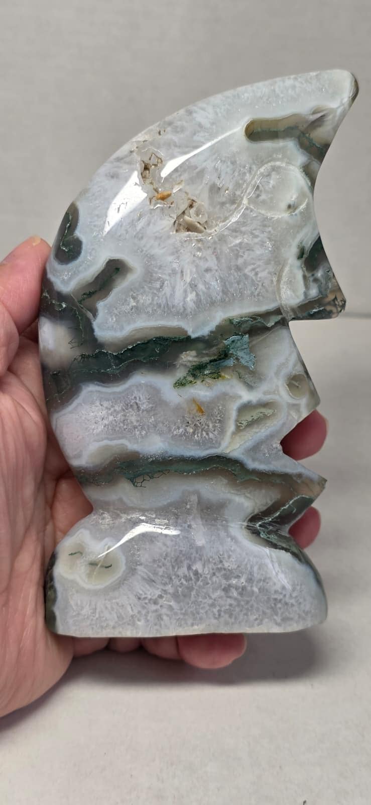 Moon face carving in moss agate, light gray with green veining, carved facial features