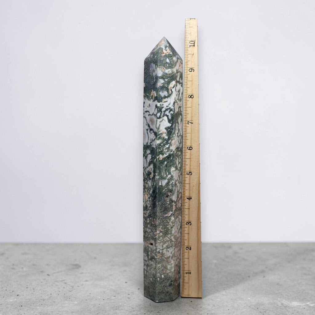 Moss agate obelisk point next to ruler, tall green-veined crystal.