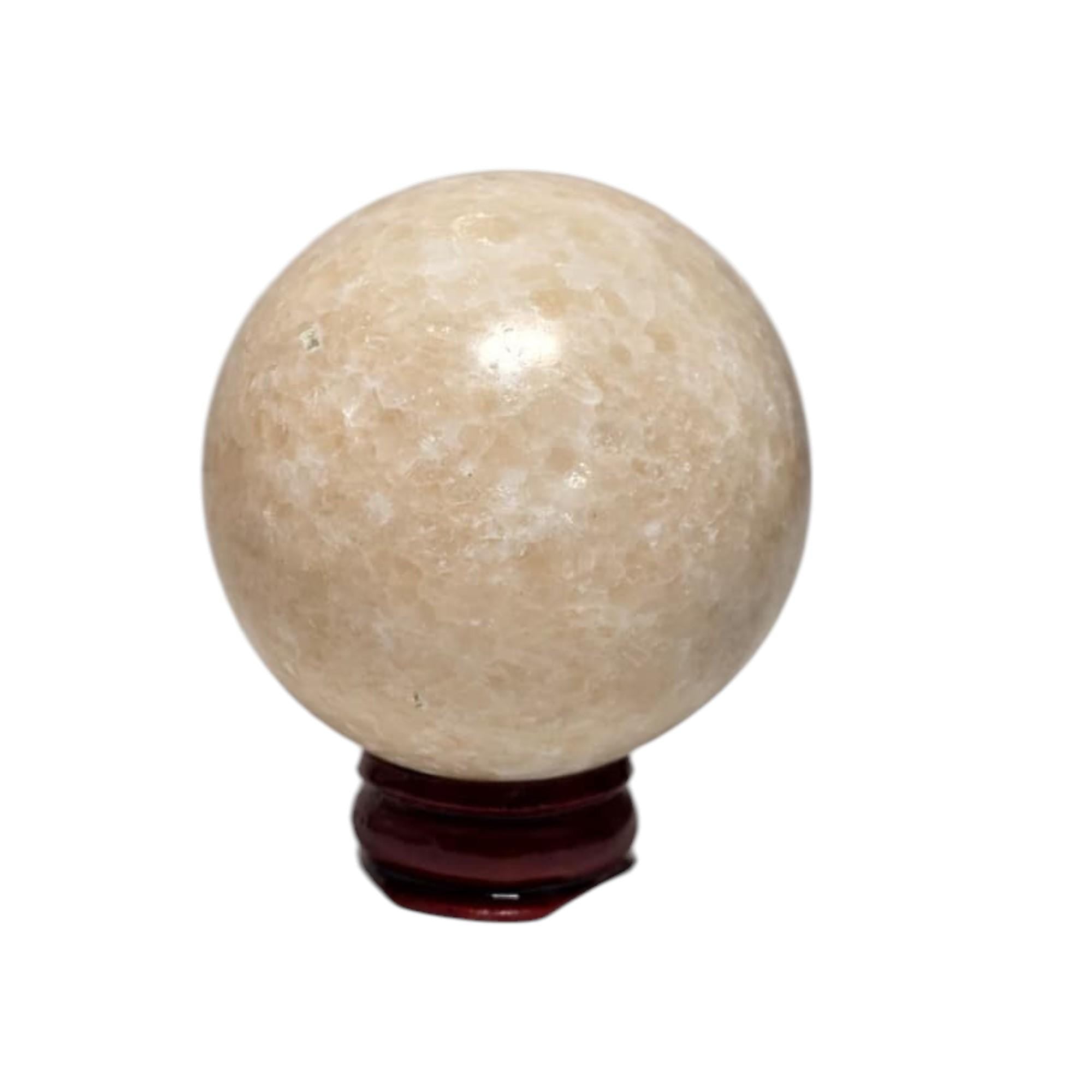 Honey calcite crystal sphere on dark base, pale honey-gold, glossy and speckled