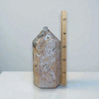 Polished ocean jasper tower with cream and tan swirls, small purple flecks; capped top.