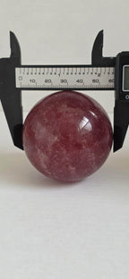 Deep red crystal sphere measured with a black caliper
