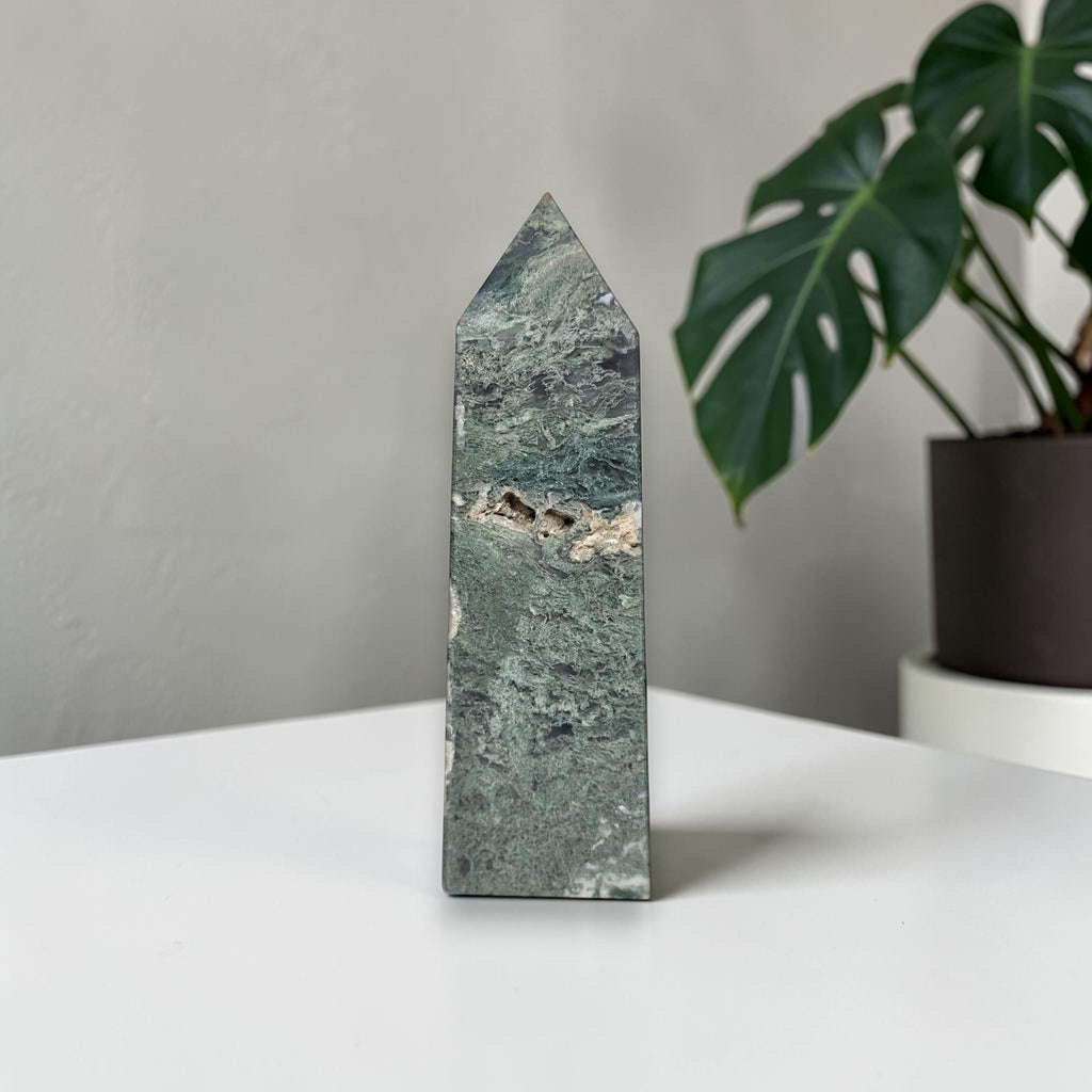 Green moss agate obelisk crystal tower with pointed top and mottled stone texture