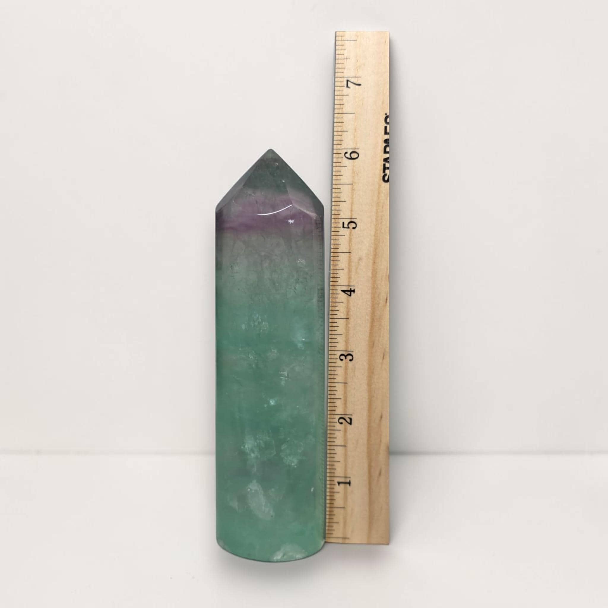 Green fluorite tower next to ruler, purple-tinted top, polished pointed crystal