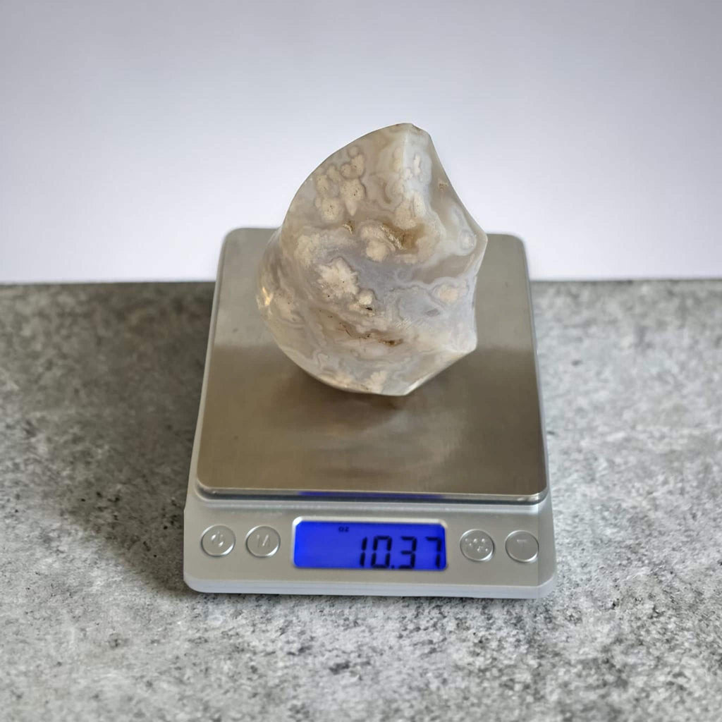 Agate flame crystal on a digital scale, clear beige with white druzy inclusions