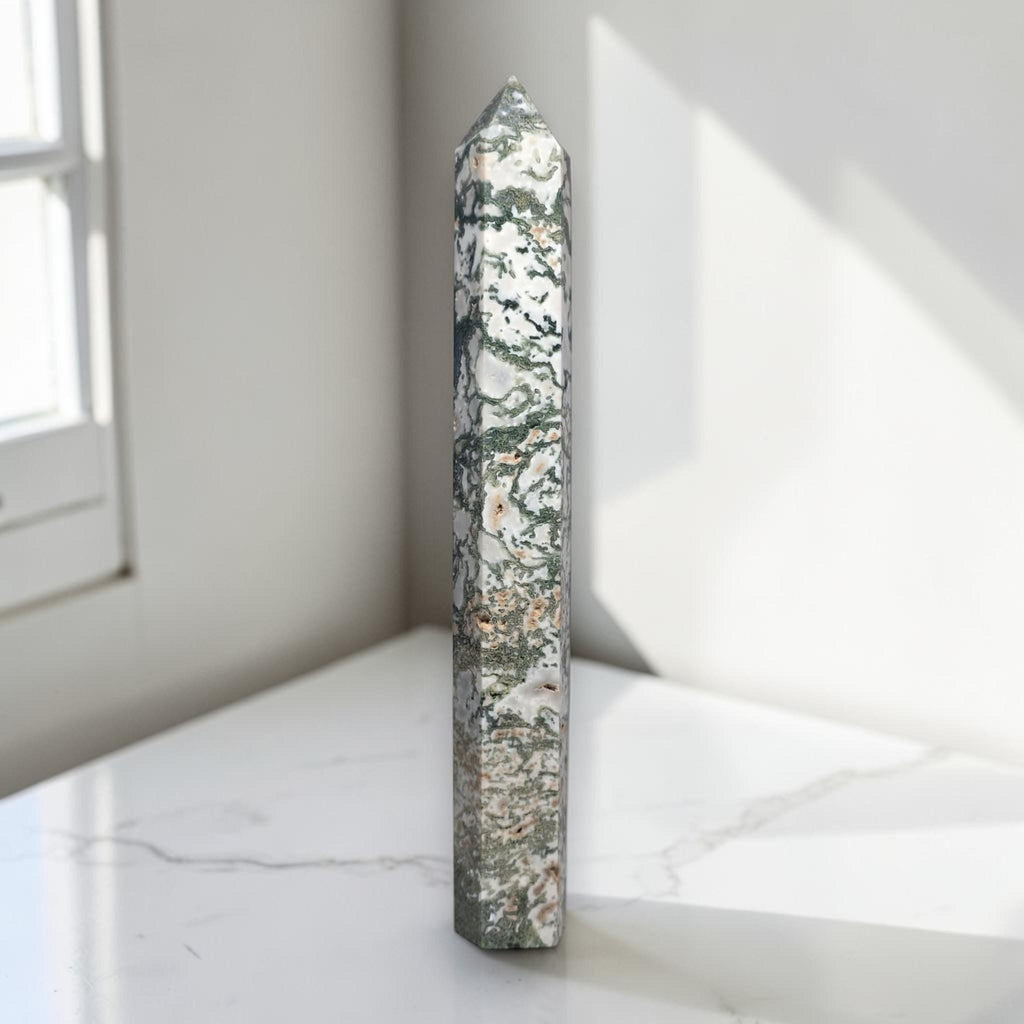 Moss agate obelisk point, slender prism with green-and-cream mottled pattern.