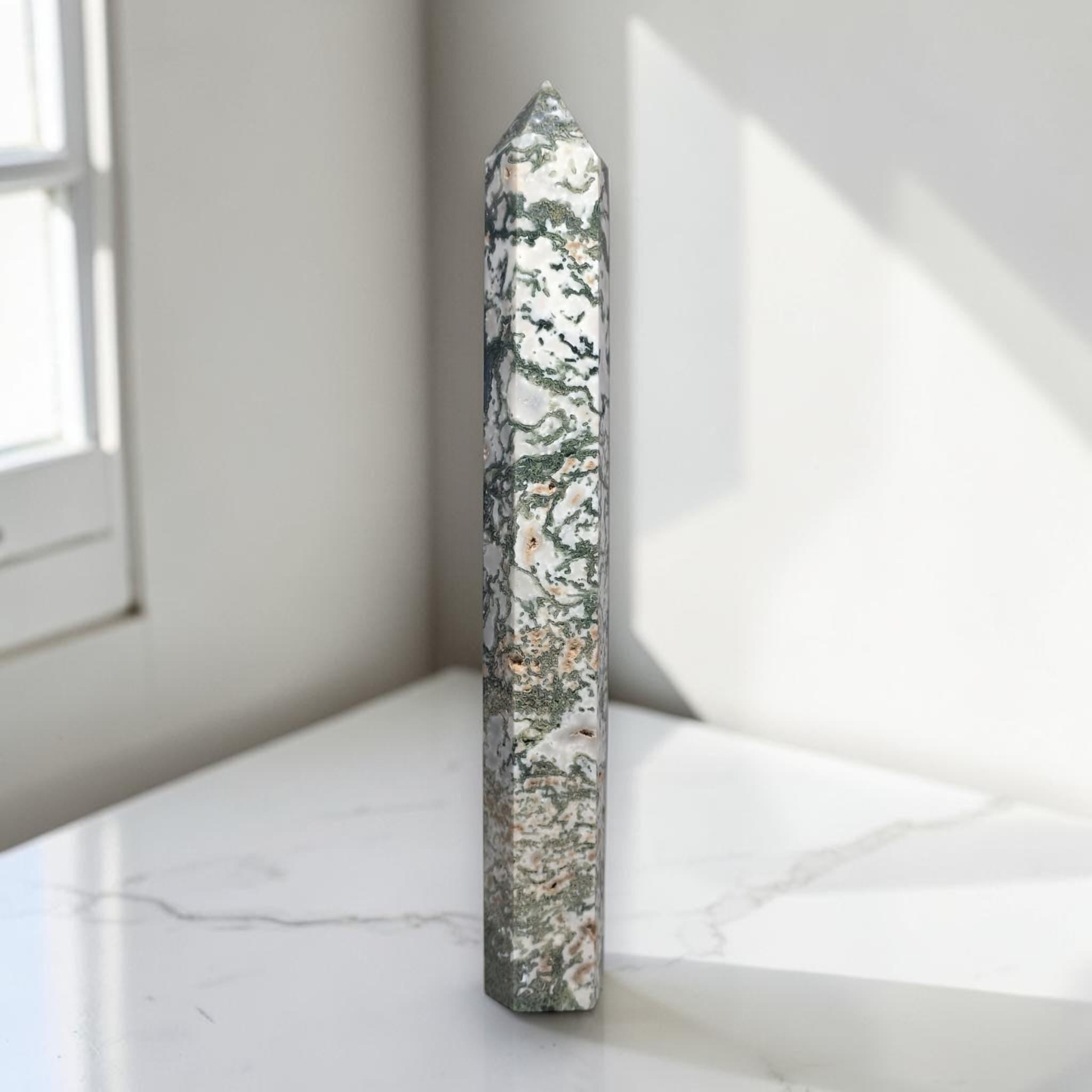 Moss agate obelisk point, slender prism with green-and-cream mottled pattern.