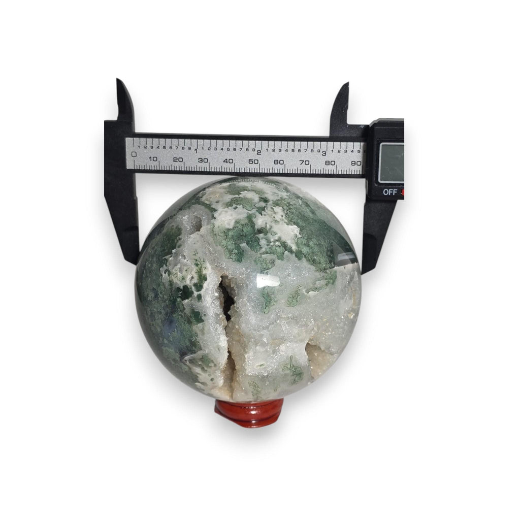 Green crystal sphere on red base with caliper measuring diameter