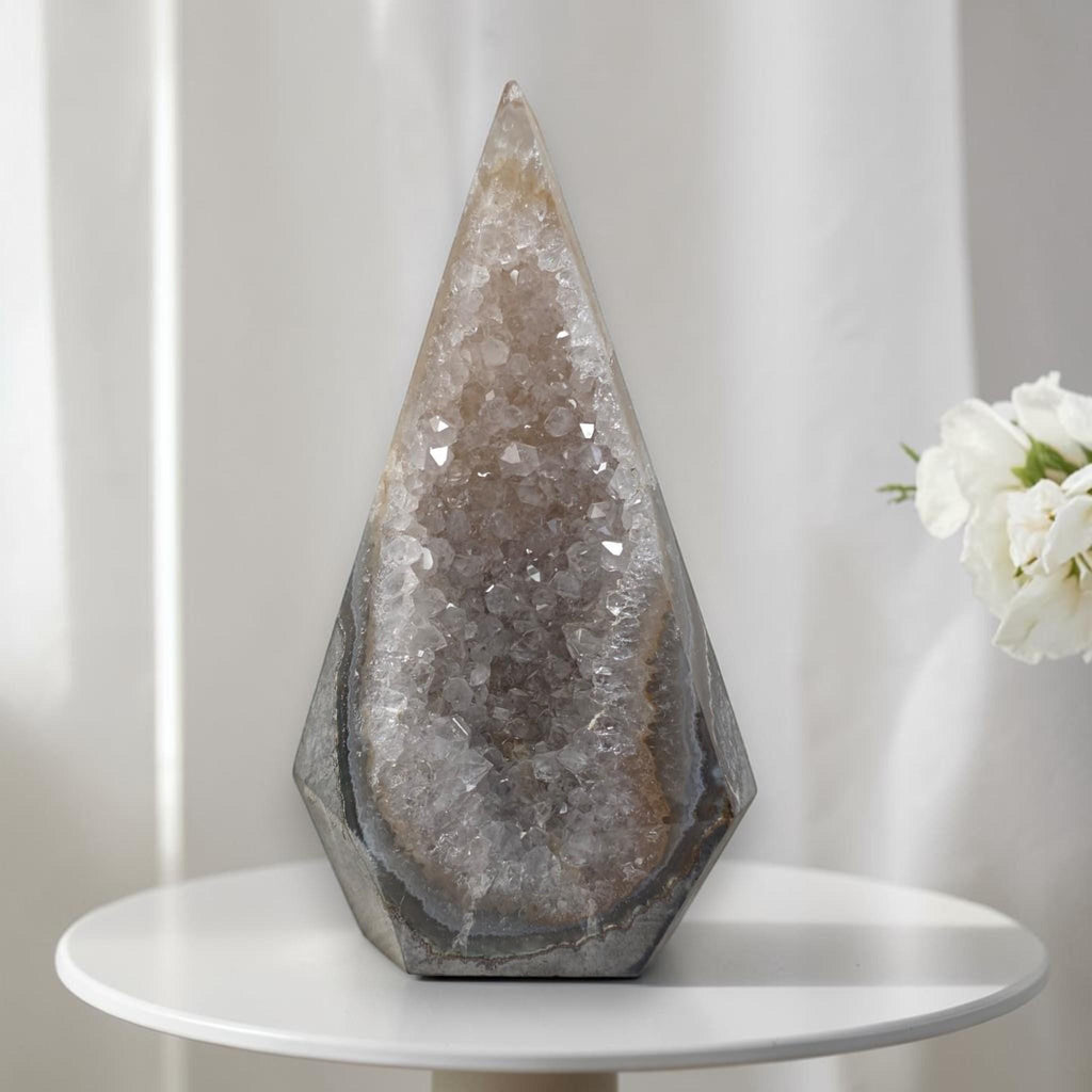 Large quartz geode tower with faceted crystal interior and dark gray stone exterior