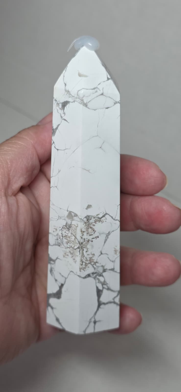 White howlite tower held in hand, gray veining, pointed top
