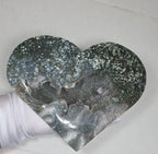 Close-up of moss agate druzy heart surface texture held in gloved hand