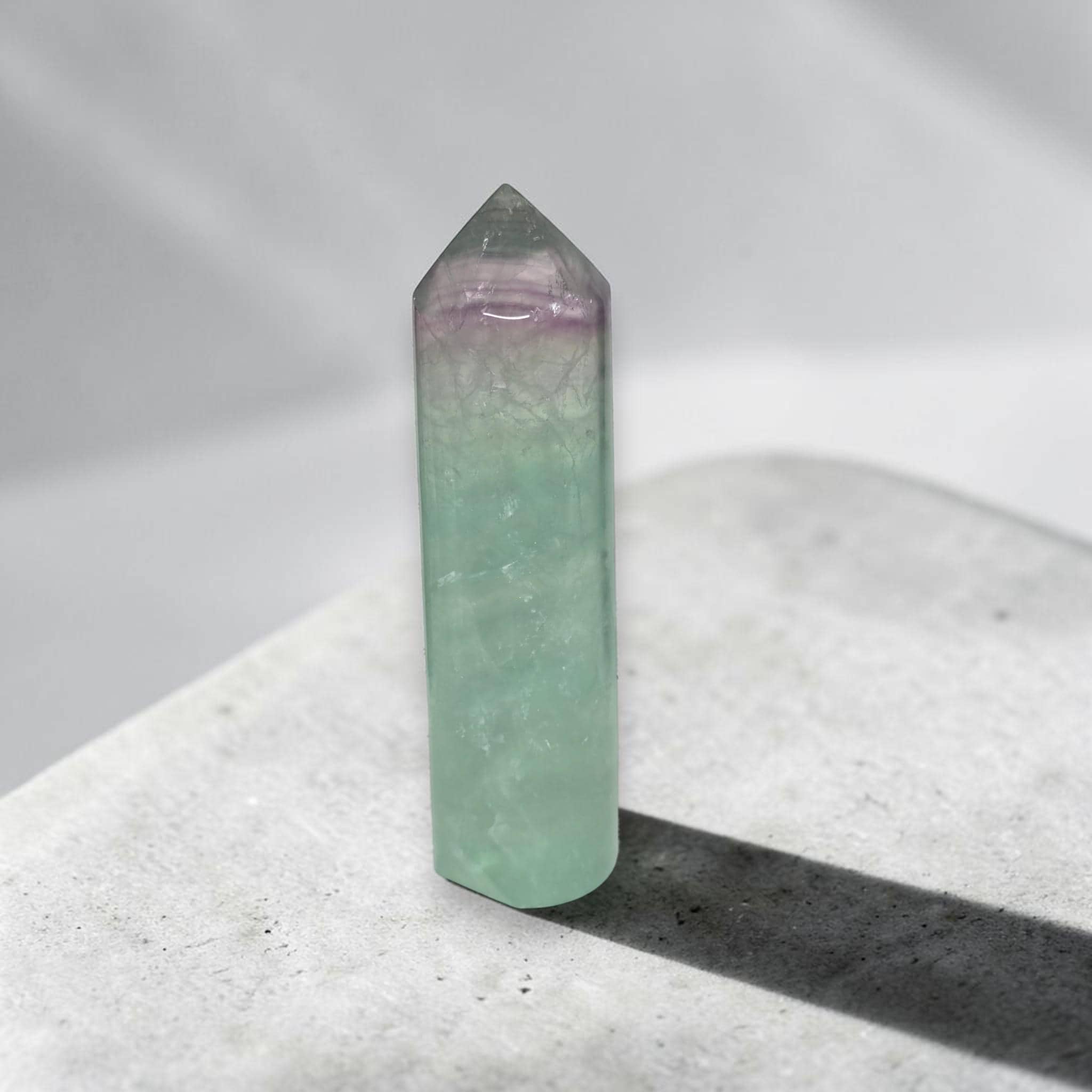 Green fluorite crystal tower with purple-tinted top, polished point and smooth sides