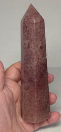 Deep red crystal point tower in hand with pointed top and flat facets