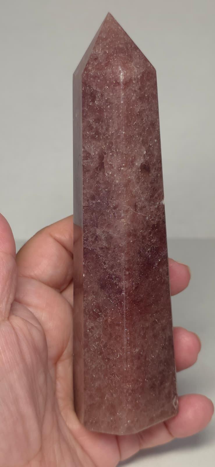 Deep red crystal point tower in hand with pointed top and flat facets