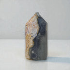 Polished ocean jasper obelisk with dark gray-blue and cream marbling, capped top.