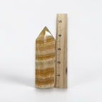 Honey-yellow calcite tower mineral point with banded layers, shown beside measuring ruler.