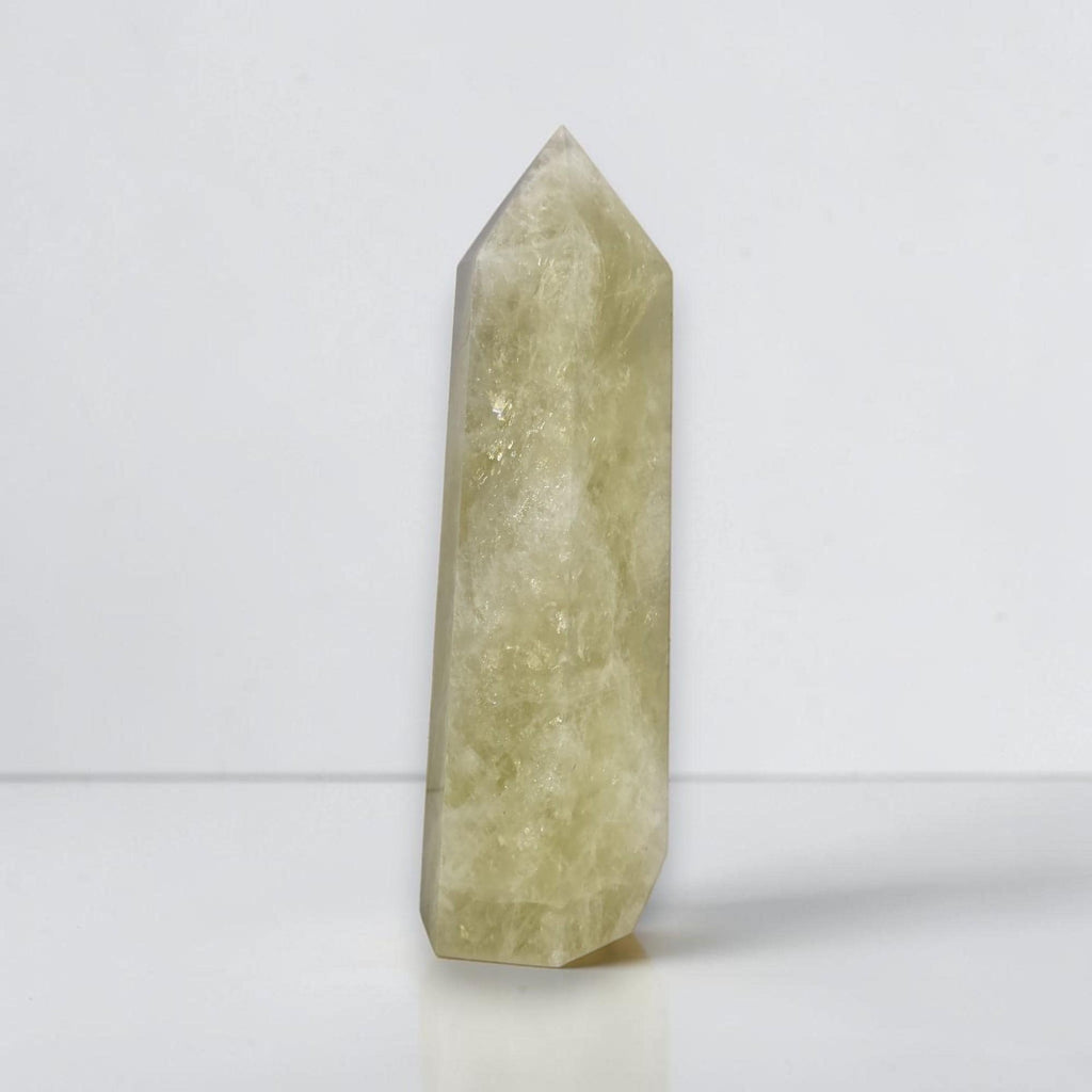 Pale yellow-green translucent crystal obelisk tower with pointed top, textured surface