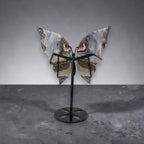 Butterfly-shaped object on a stand against a gray background