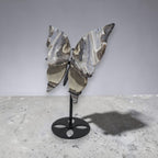 Decorative butterfly sculpture on a stand against a plain background