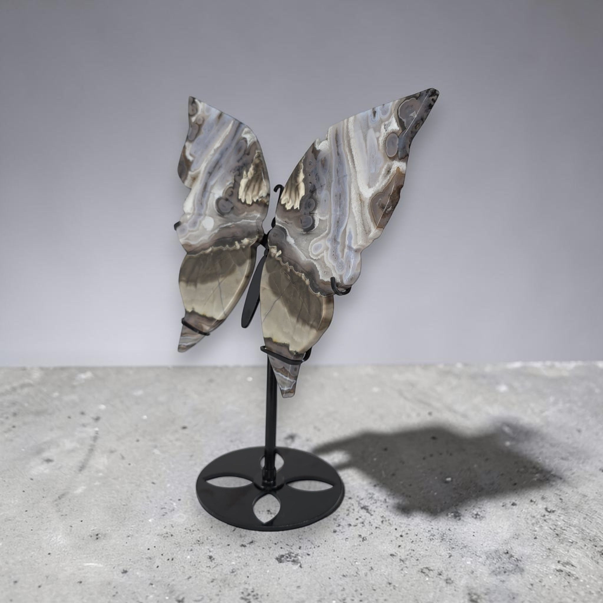 Decorative butterfly sculpture on a stand against a plain background