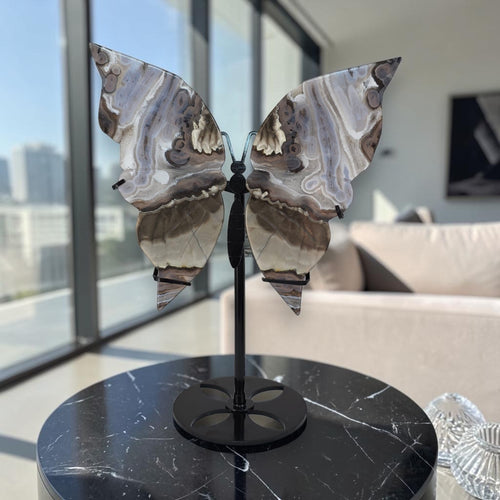 Butterfly-shaped decorative object on a black marble surface with a cityscape view.