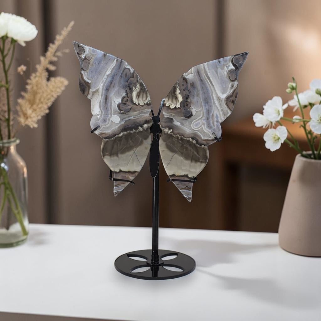 Decorative butterfly sculpture on a stand with flowers in the background