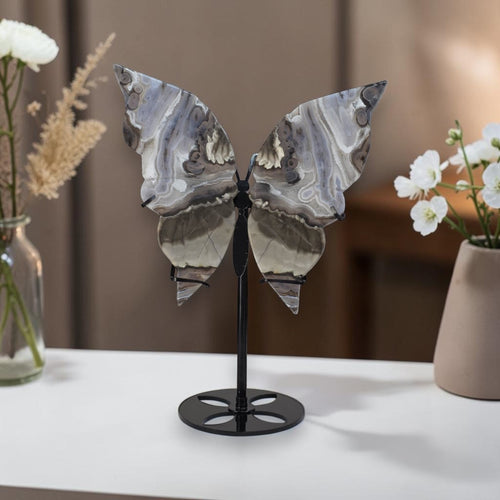 Decorative butterfly sculpture on a stand with flowers in the background