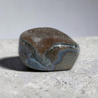 Polished stone with blue and brown patterns on a concrete surface