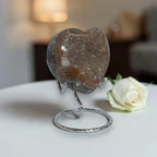 Heart-shaped crystal on a stand with a white rose in the background