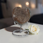 Heart-shaped stone on a stand with a white rose on a blurred background