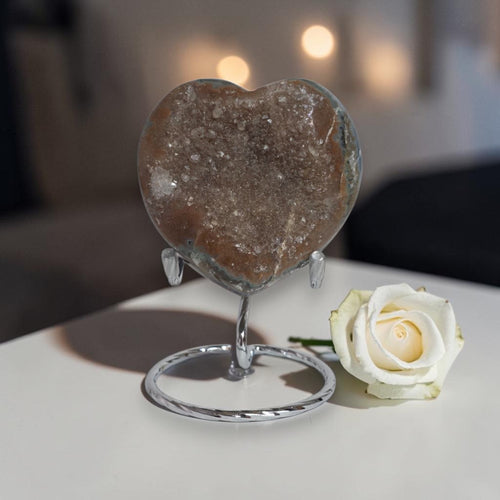 Heart-shaped stone on a stand with a white rose on a blurred background