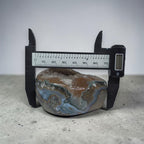 Digital caliper measuring a textured stone on a concrete surface