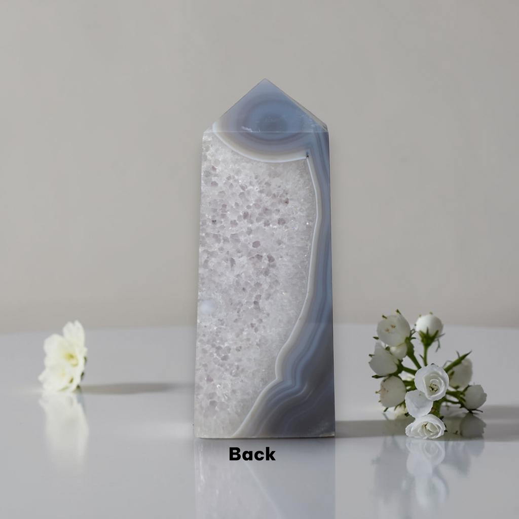 Decorative vase with a textured design on a reflective surface with flowers.