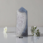 Decorative vase with a textured design on a reflective surface with flowers.